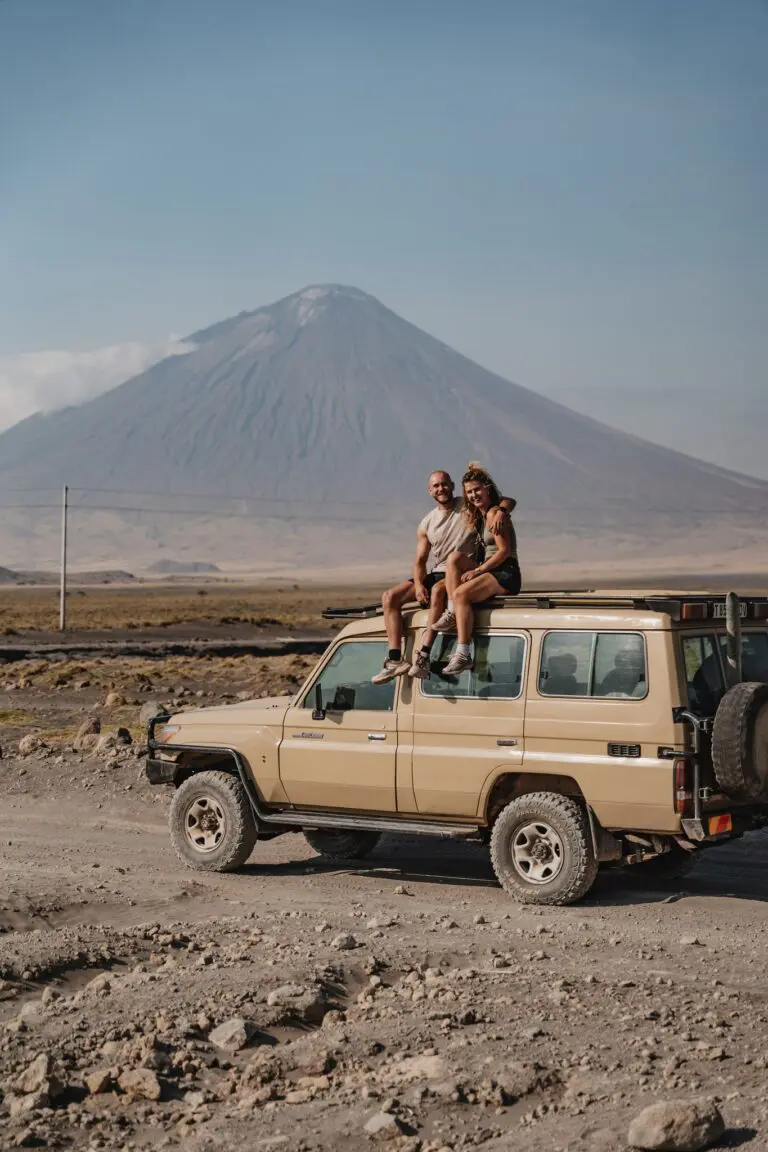 couple sur le toit d’une jeep de safari, volcan en arrière-plan