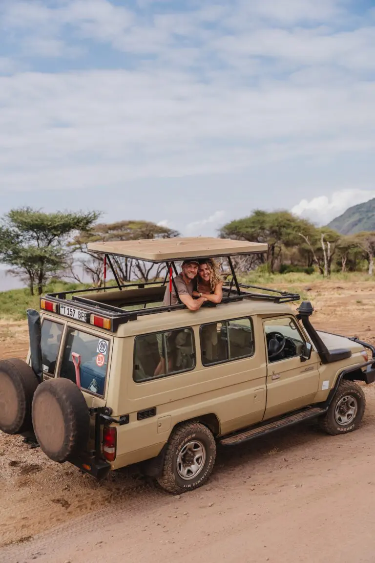 couple on safari in Tanzania looking out of pop-top vehicle