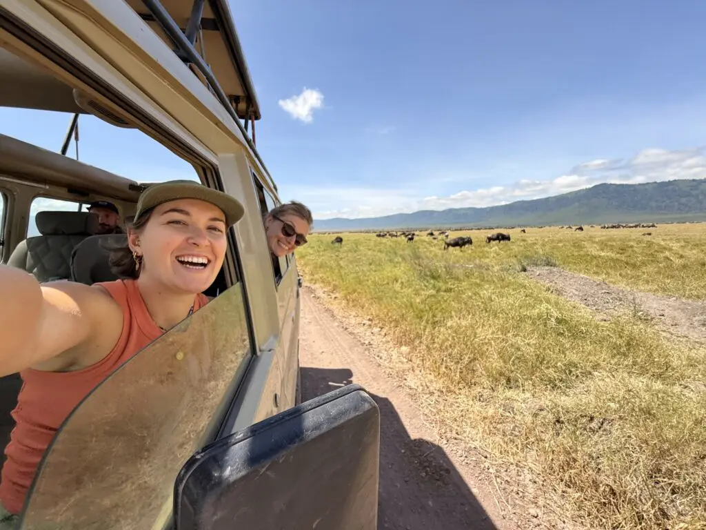 two women on safari in Tanzania with a wildebeest herd